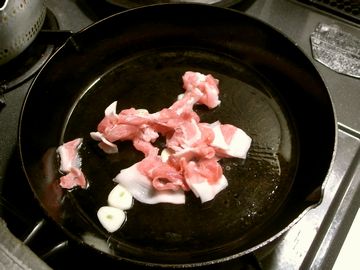 フライパンでニンニク豚肉を炒める